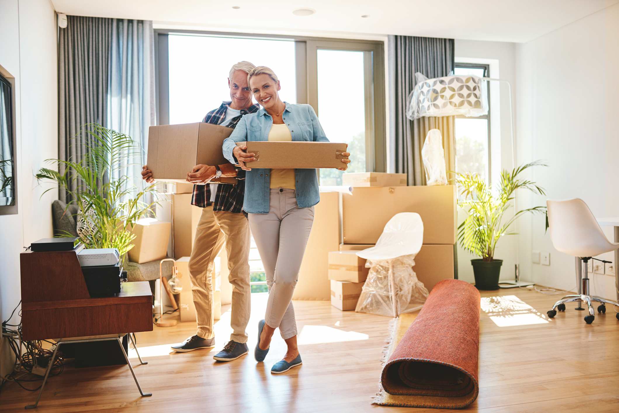 A couple carrying moving boxes into their new home