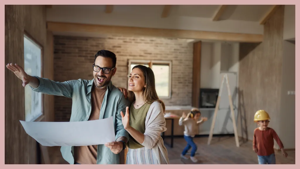 A young family standing inside a home under construction while reviewing architectural plans. Parents point toward the future layout as their children explore the unfinished space, illustrating the planning process involved with a One Time Close construction loan that finances the land, construction, and permanent mortgage in a single loan.