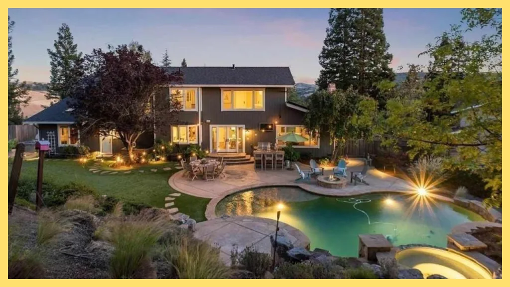 Luxury California home with a resort style backyard featuring a freeform swimming pool, spa, fire pit, outdoor dining area, and landscaped gardens at dusk, illustrating how homeowners can transform a property over time through strategic renovations and long term homeownership.