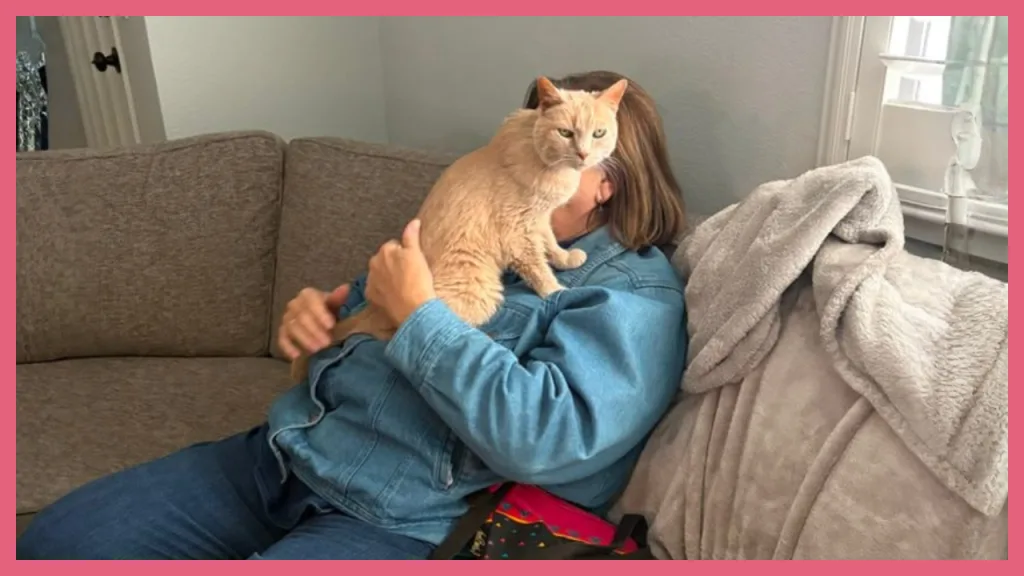 A woman relaxing on a living room sofa while holding an affectionate orange cat in her lap. The cozy scene represents the comfort and stability of a multigenerational home in Placerville, California, where an FHA home purchase and an ADU created space for family to live together while maintaining independence.
