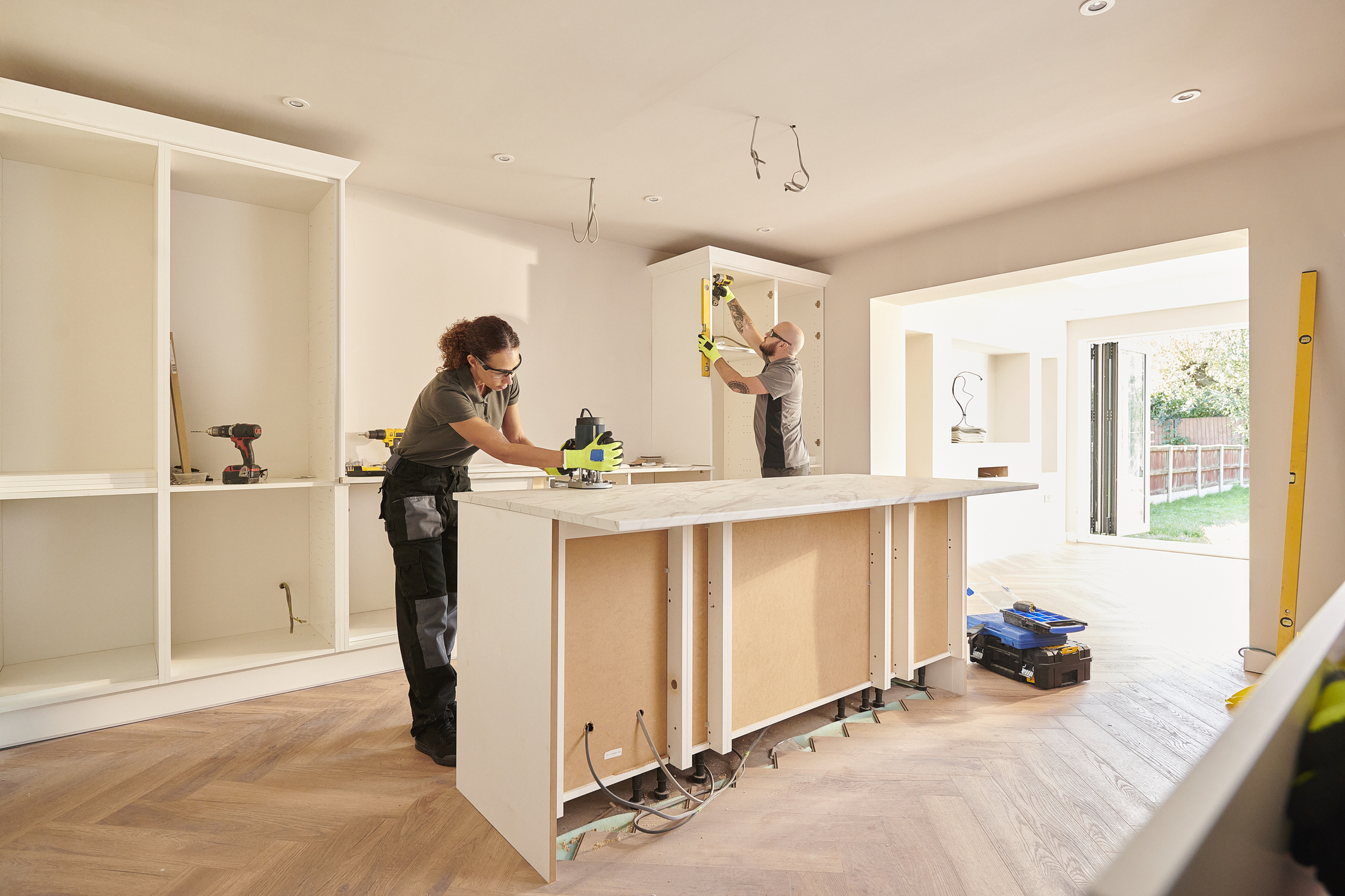 Two contractors installing cabinets and a kitchen island during a home renovation