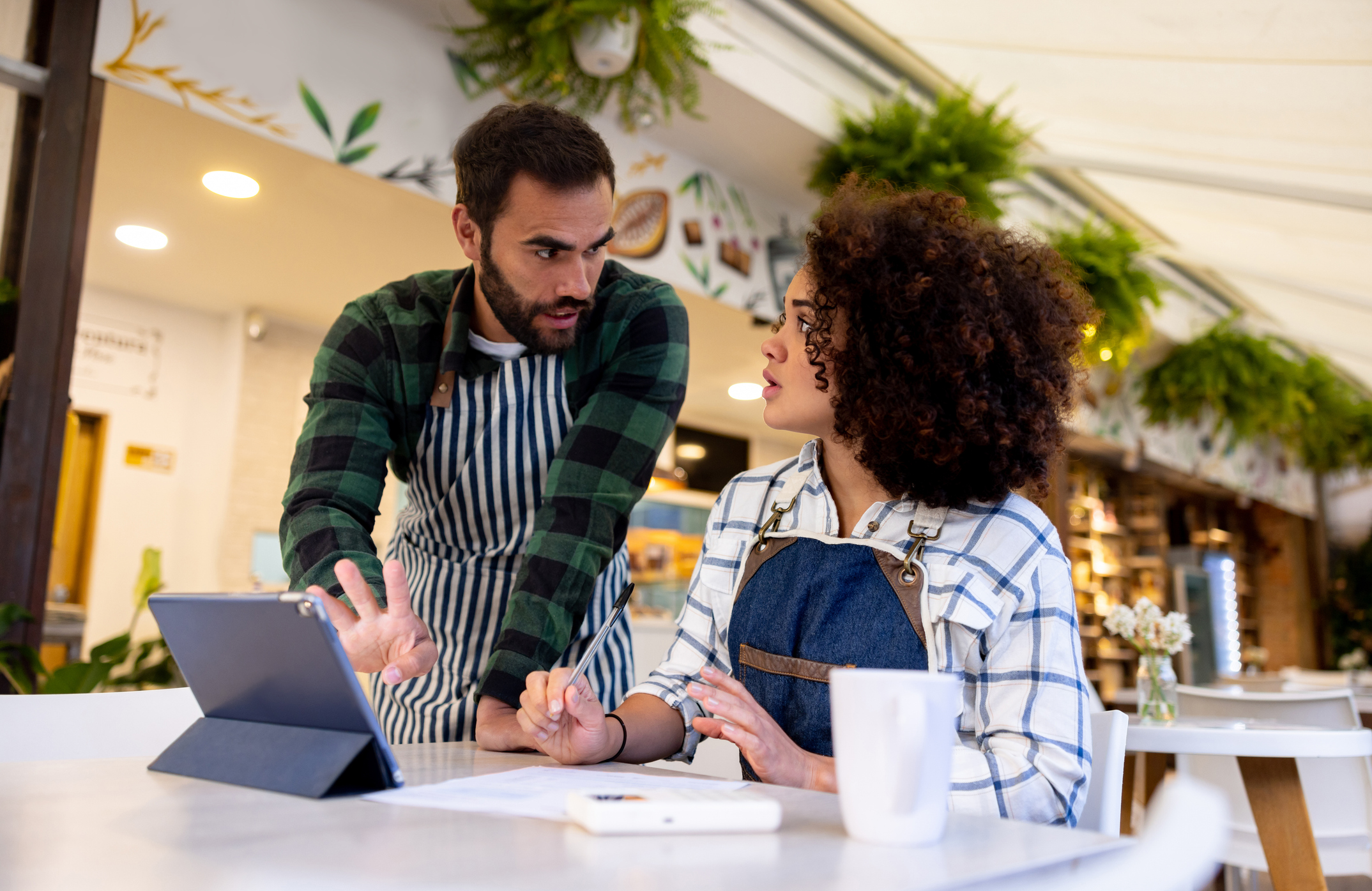 Two cafe owners reviewing paperwork and a tablet together